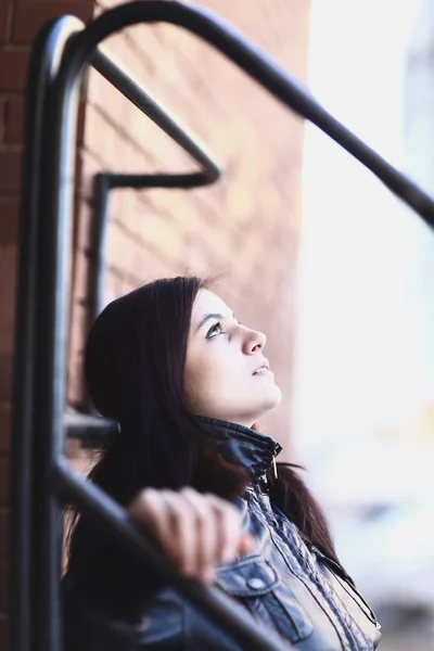 Portrait of a young woman leaning against a wall of a city building — Stock Photo, Image