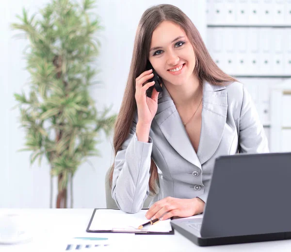 Asistente femenina hablando por teléfono sentado detrás de un escritorio — Foto de Stock