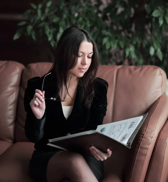 Элегантная деловая женщина, просматривающая финансовые документы в современном бизнес-центре — стоковое фото