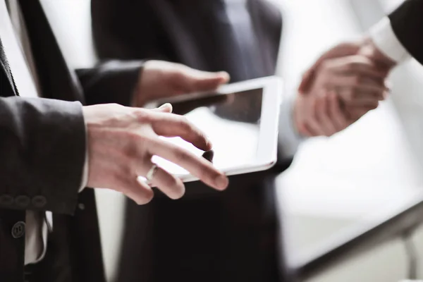 Zakenman met digitale tablet in de achtergrond van handdruk van zakelijke partners — Stockfoto