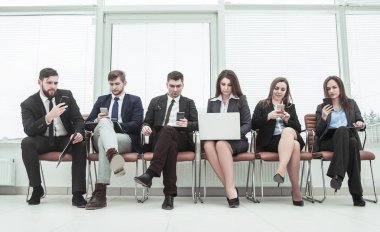 bir smartphone ve modern ofis lobisinde otururken dizüstü kullanarak internette bilgi arayan iş takım