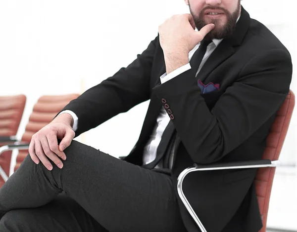 Hombre de negocios guapo sentado en una silla en una sala de conferencias — Foto de Stock