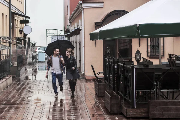 Pareja amorosa bajo un paraguas caminando por la calle de la ciudad vieja — Foto de Stock