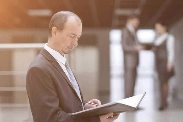 Geschäftsmann mit Klemmbrett beim Lesen eines Arbeitsdokuments. — Stockfoto