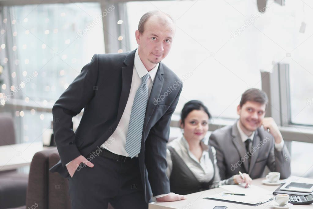 close up.confident businessman standing near desktop