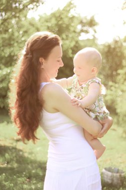 Anne ve mutlu bir yaşındaki kızı parkta bir yürüyüş üzerinde gülümseyen