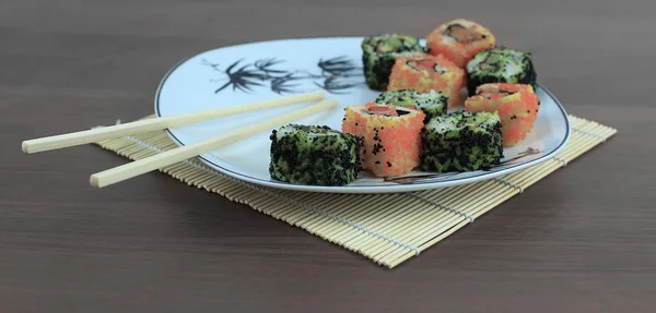 Close-up de sushi e pauzinhos em uma placa branca — Fotografia de Stock