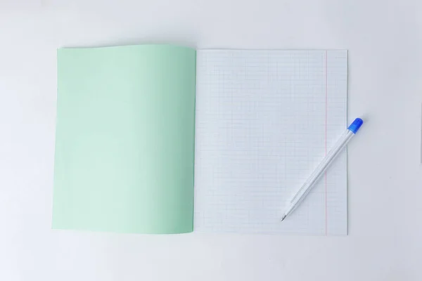 Close up.open caderno escolar em uma gaiola e uma caneta esferográfica .photo com espaço de cópia — Fotografia de Stock