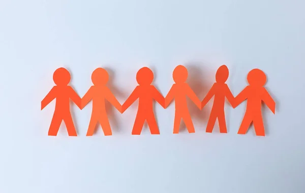 Four paper men taking each others hands — Stock Photo, Image