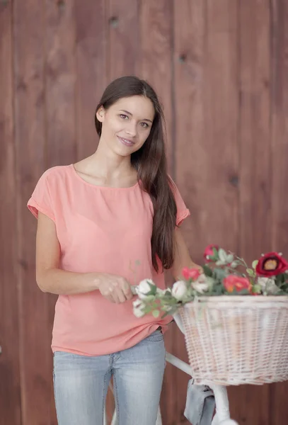 Junge Frau mit Fahrrad mit einem schönen Korb voller Blumen — Stockfoto