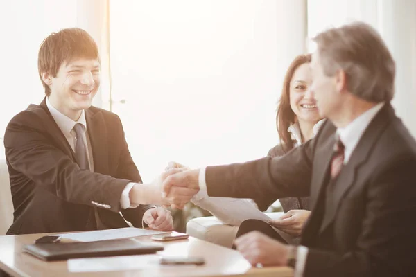 Handslag för affärspartners som sitter vid ett skrivbord — Stockfoto