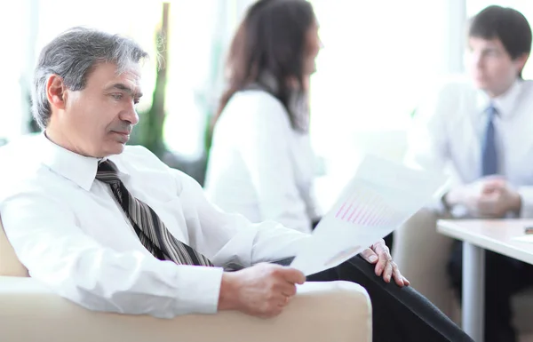 Homme d'affaires réfléchissant à un document assis dans un bureau moderne — Photo