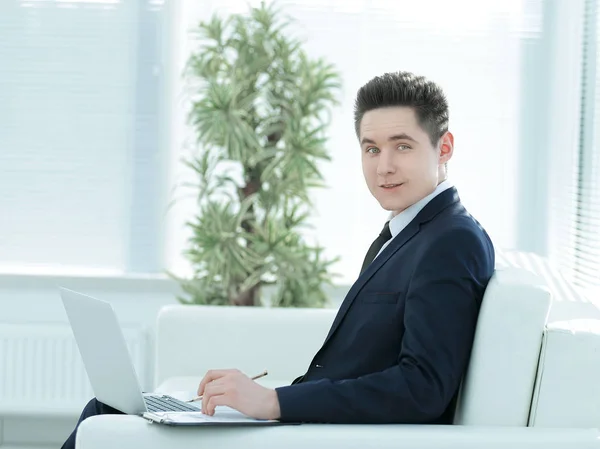 Handsome businessman with open laptop sitting in the lobby of th — Stock Photo, Image