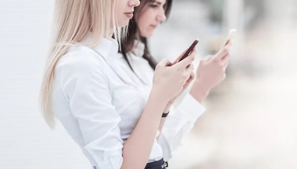 Genç kadın çalışanlar şirketin bir smartphone cep telefonu ile bilgi alışverişi — Stok fotoğraf