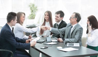 welcome handshake of business partners at the negotiating table clipart