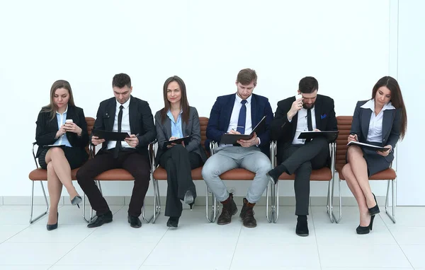 Бизнес-команда с буферами обмена, сидящими в ряд — стоковое фото
