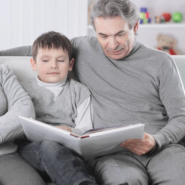 Abuela y abuelo leer libro a su nieto. El concepto de educación —  Fotos de Stock