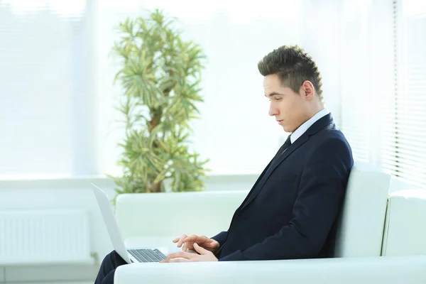 Yakışıklı işadamı th lobisinde otururken dizüstü bilgisayarda yazarak — Stok fotoğraf