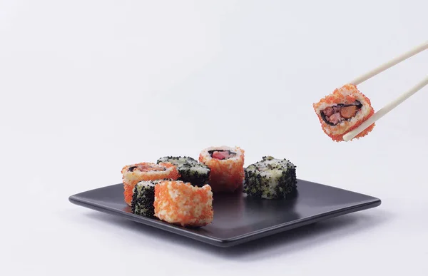 Sushi e rolos. o conjunto é servido em uma placa preta — Fotografia de Stock