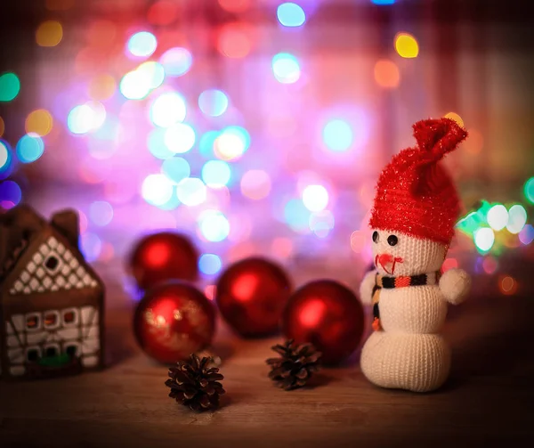 Muñeco de nieve de juguete y casa de jengibre en la mesa de Navidad — Foto de Stock