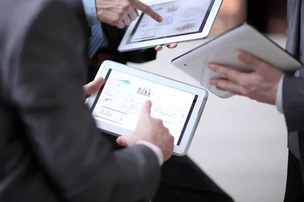 Close up.a group of businessmen use their tablets to check financial data — Stock Photo, Image