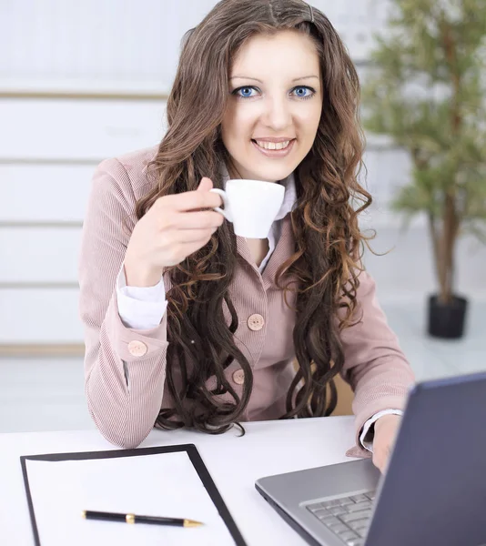 Leende affärskvinna med kaffekopp som sitter vid ditt skrivbord. — Stockfoto