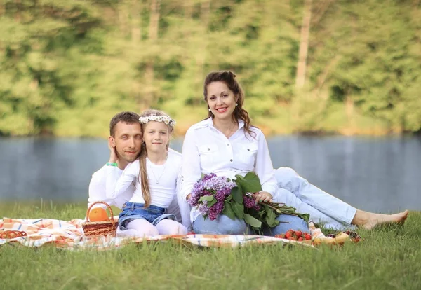 Gelukkig vader van een dochter en een zwangere moeder op een picknick. — Stockfoto