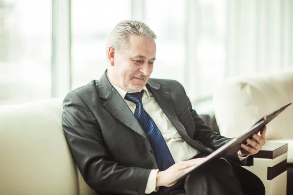 Erfolgreicher Geschäftsmann studiert Arbeitspapiere auf dem Sofa im Privatbüro — Stockfoto