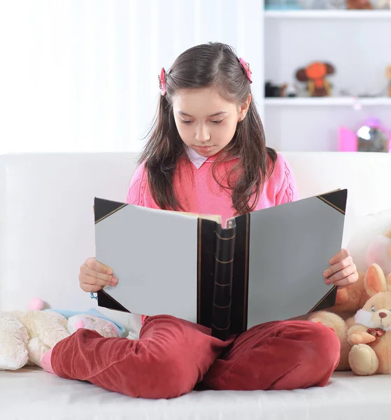 Mädchen liest ein Buch auf der Couch im Kinderzimmer — Stockfoto