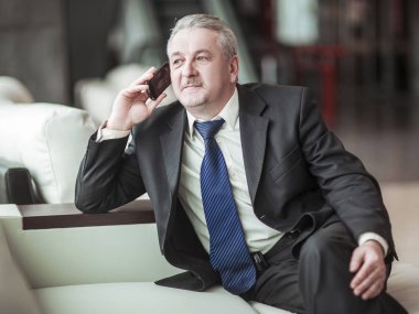 ofiste kanepede oturan onun smartphone cep telefonu ile konuşurken başarılı iş adamı