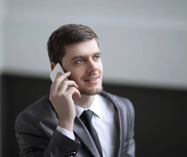 Close up. smiling businessman talking on smartphone in office — стоковое фото