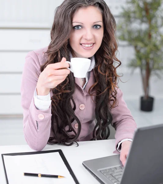 Leende affärskvinna med kaffekopp som sitter vid ditt skrivbord. — Stockfoto