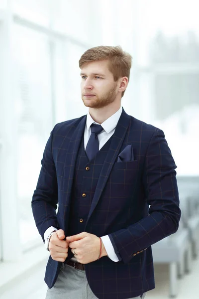 Pensive young businessman standing near the office window — Stock Photo, Image