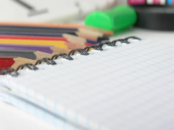 Close-up da imagem borrada do bloco de notas quadriculado e lápis no fundo branco — Fotografia de Stock