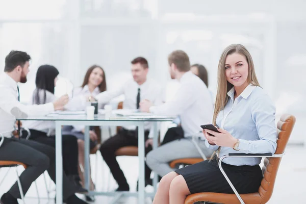 Joven empleado con un teléfono inteligente en el fondo del equipo de negocios — Foto de Stock