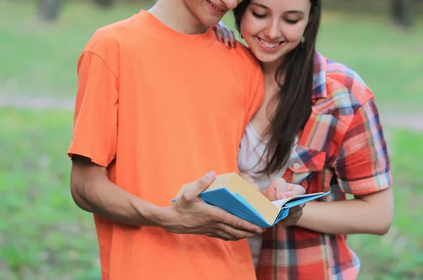 Двое студентов читают книгу, стоящую в парке — стоковое фото