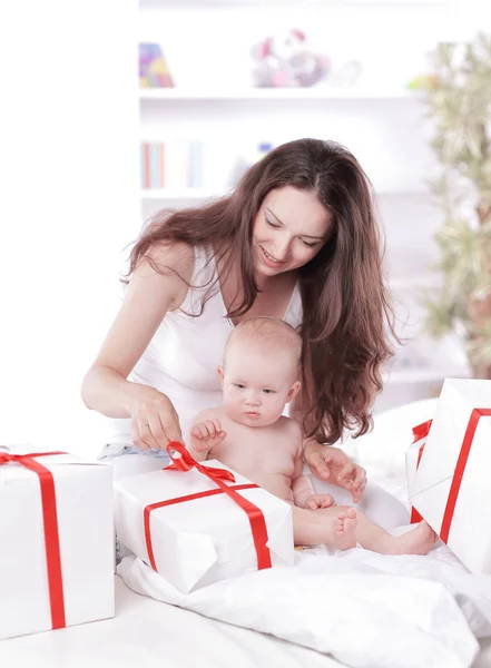 Young mother unties the ribbon on the gift boxes — Stock Photo, Image