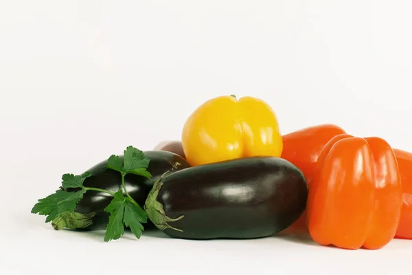 Paprika, aubergines en takjes peterselie op een witte pagina — Stockfoto