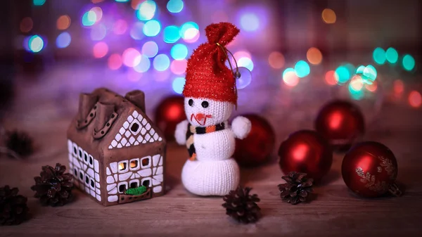 Muñeco de nieve de juguete y casa de jengibre en la mesa de Navidad — Foto de Stock