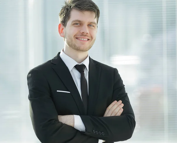 Jeune homme d'affaires souriant sur fond flou bureau — Photo