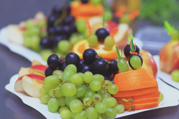 Close up.plate with grapes and oranges on blurred background — Stock Photo, Image