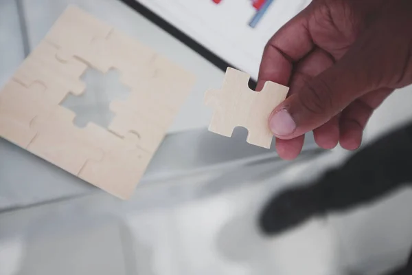 Close-up. de zakenman is een puzzel, zitten achter een bureau. — Stockfoto