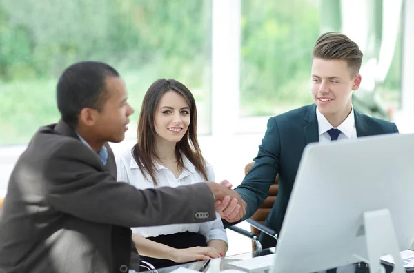 Apretón de manos socios comerciales internacionales en un escritorio — Foto de Stock