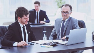 patron ve çalışanın ofis masasında oturan belge tartışıyor.