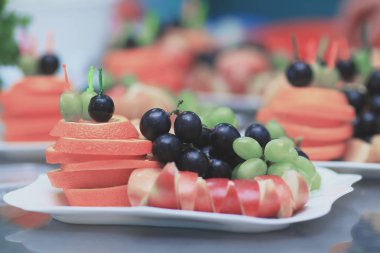 yakın up.Apples, portakal ve üzüm bir plaka üzerinde