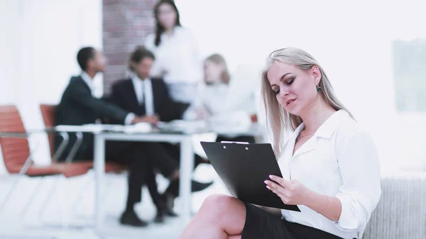 Kvinnlig assistent med av protokollet från mötet på bakgrunden av kontoret — Stockfoto