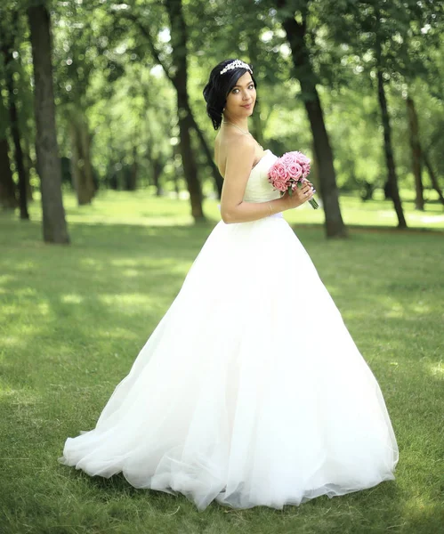 В полном росте. невеста с букетом, стоящая в парке — стоковое фото