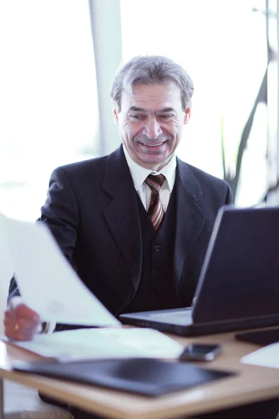 Lächelnder Geschäftsmann sitzt an seinem Schreibtisch — Stockfoto