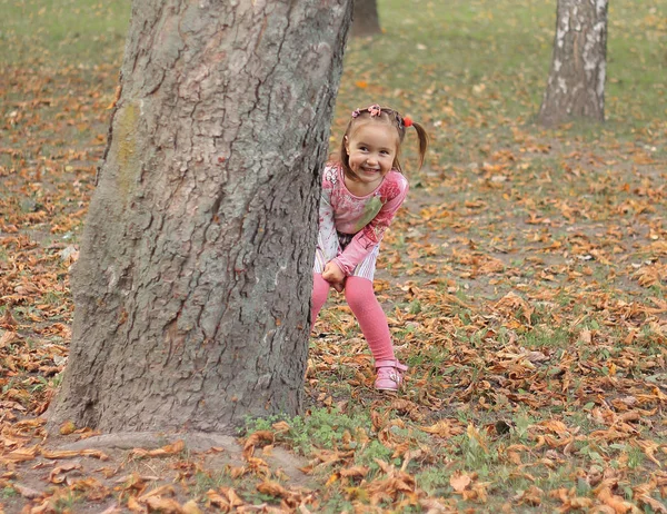 Gelukkig klein meisje spelen verstoppertje in de stad Park — Stockfoto