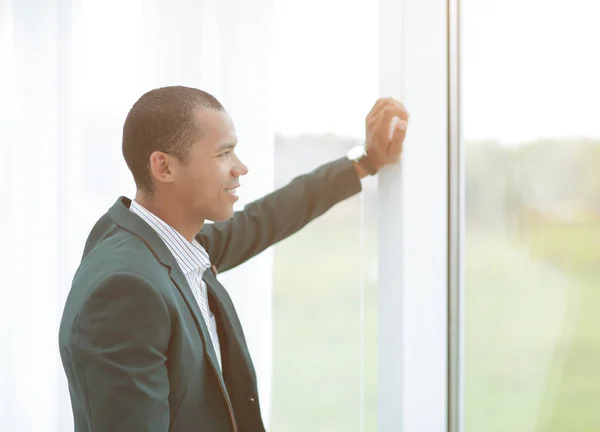 Exitoso joven empresario mirando a la ventana de la oficina en blanco —  Fotos de Stock